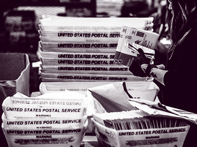 person holding ballots with postal boxes